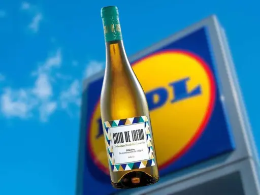 Botella de vino blanco Coto de Ibedo con etiqueta colorida, frente a un cartel de Lidl.
