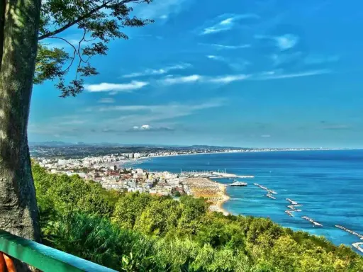 Vista panoramica della Riviera Romagnola con mare azzurro, spiagge affollate e una città costiera. Ideale per il turismo.