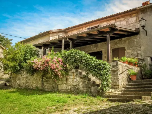 Steinhaus mit blühenden Rosen und Efeu in einem malerischen Dorf in Hum, Kroatien.