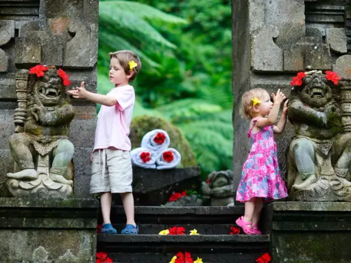 Bambini a Bali esplorano antiche statue decorate con fiori. Un'avventura indimenticabile per i più piccoli.