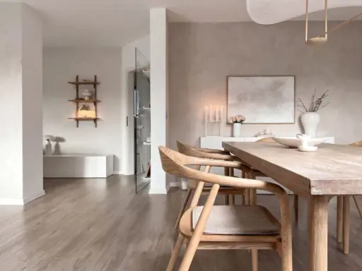 Interni in stile wabi sabi con tavolo in legno grezzo, sedie in legno chiaro e decorazioni minimaliste.