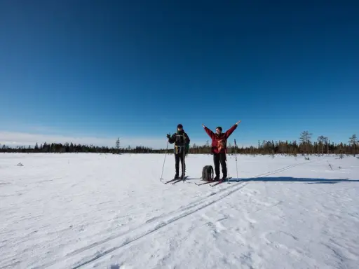 Två skidåkare njuter av en solig dag i Koppången naturreservat.