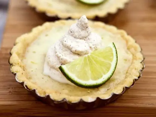En liten key lime pie med en virvel av gräddig topping och en limeklyfta.