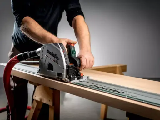 Main d'un artisan guidant une scie circulaire sur un rail pour une coupe précise sur une planche de bois.