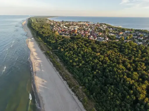 Piękna plaża i las, idealne miejsce, gdzie na majówkę. Widok z lotu ptaka na nadmorską miejscowość.