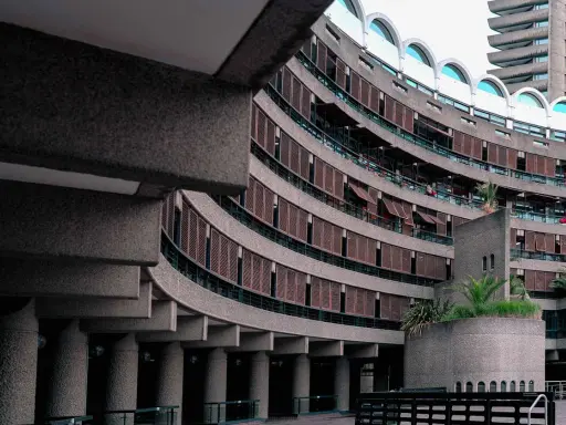 Edifici curvi in cemento con persiane in legno al Barbican Centre. Un'architettura iconica che si staglia nel cielo.