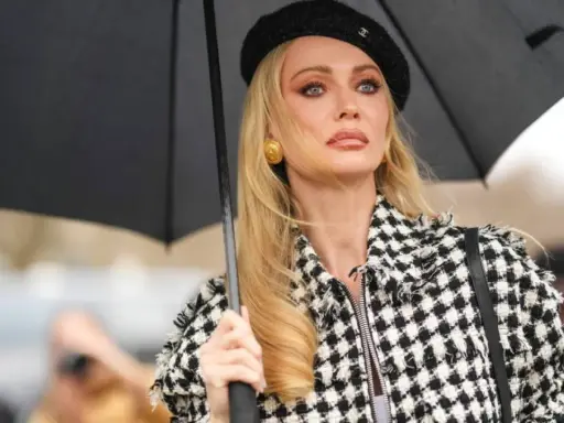 Mujer con boina negra y chaqueta a cuadros, sosteniendo un paraguas. Su maquillaje es un perfecto ejemplo de soft glam.