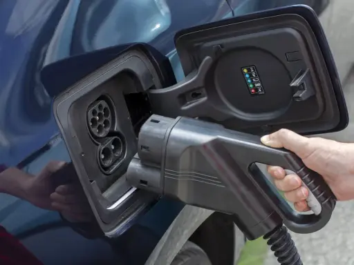 Mano insertando cargador en coche eléctrico. Averigua cuanto tarda en cargar un coche eléctrico en casa.