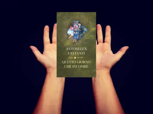 Mani aperte sorreggono la copertina del libro "Questo giorno che incombe", con una famiglia distesa sull'erba.