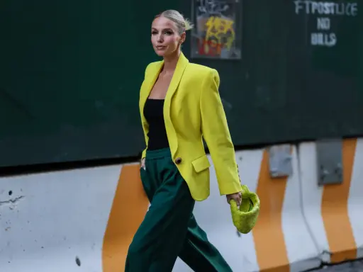 Kobieta w żółtej marynarce i zielonych spodniach, z limonkową torebką. Jej stylizacja to prawdziwe koło kolorów ubrania, łączące energię i elegancję.