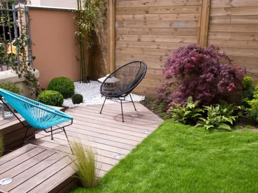 Aménagement d'un petit jardin de 100m2 : terrasse en bois, mobilier design, gazon et végétation luxuriante pour un espace détente moderne.