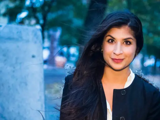 Soraya Hashim ler mot kameran, hennes mörka hår blåser i vinden.