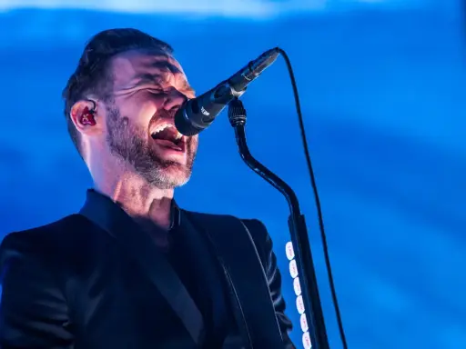 Jocke Berg från Kent sjunger passionerat in i mikrofonen, klädd i en svart kavaj.