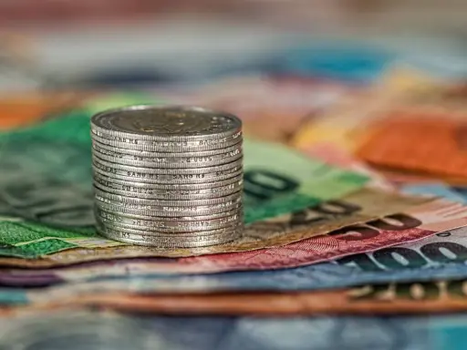 Stos monet na kolorowych banknotach. Czy to symbol najlepiej płatnych zawodów w Norwegii?