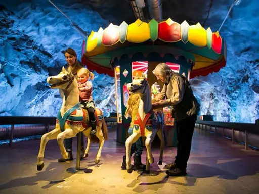 Familj njuter av en karusell i en grottliknande miljö på Stockholm Toy Museum.