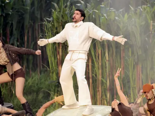 Bad Bunny's iconic bad bunny super bowl outfit, a white ensemble with a "64" on the sweatshirt, stands out against a backdrop of tall green stalks.