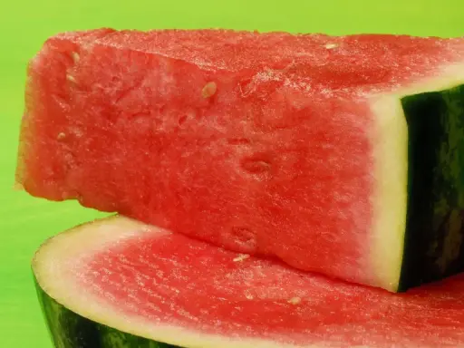 Saftige Wassermelonenstücke auf grünem Hintergrund. Perfekt für eine leichte Erfrischung, da Wassermelone kalorienarm ist.