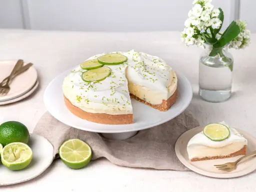 Un cheesecake au citron vert, garni de crème fouettée et de fines tranches de citron vert. Le fromage idéal pour un cheesecake est crémeux et légèrement acidulé.
