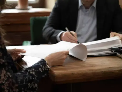 Kobieta i mężczyzna przy biurku przeglądają dokumenty. Sprawa alimentów, gdy nie płaci alimentów kiedy do komornika, wymaga analizy papierów.