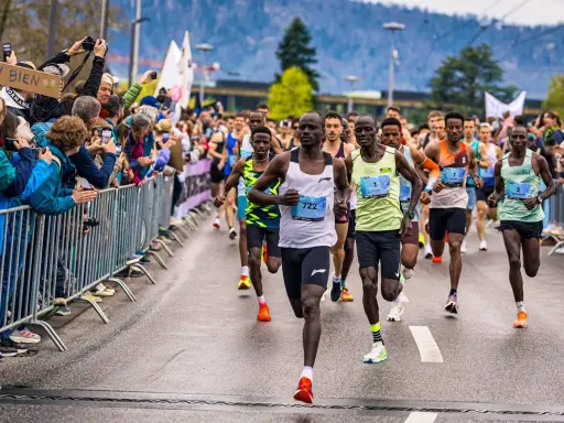 Läufer im Vordergrund einer Marathon-Geschichte, Zuschauer feuern sie an.