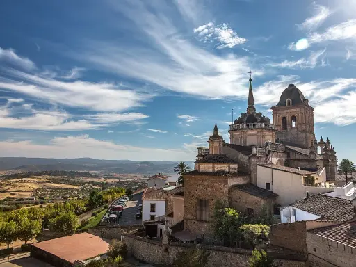 Blick auf die historische Stadt Jerez de los Caballeros mit ihren beeindruckenden Kirchtürmen unter einem dramatischen Himmel.