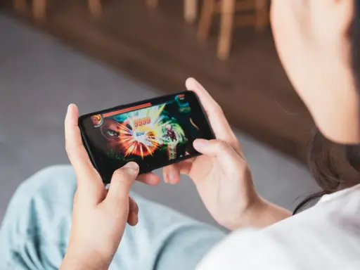 Osoba gra w ekscytujące gierki na telefon, skupiona na walce z potworem na ekranie.