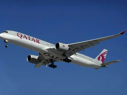 Samolot Qatar Airways z wysuniętym podwoziem, gotowy do lądowania. Idealny do podróży z bagażem podręcznym.