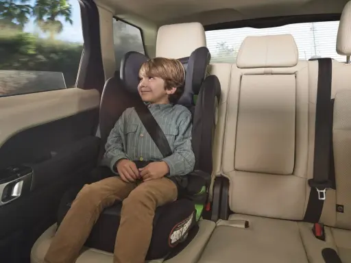 Niño sonriente en una silla de coche grupo 3 edad, viajando seguro y cómodo en el asiento trasero de un vehículo.