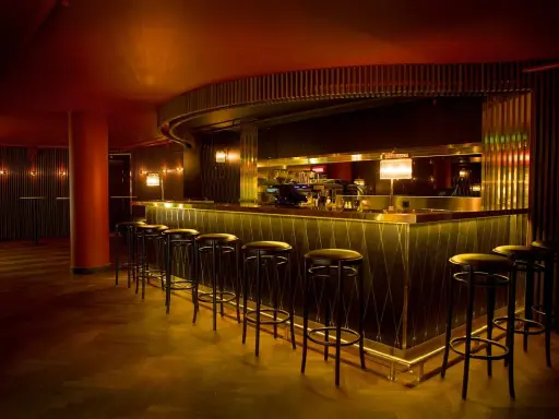En elegant bar med gulddetaljer och barstolar, perfekt för en kväll på Rigoletto Stockholm.