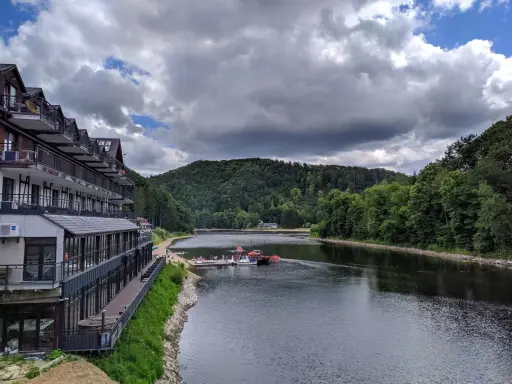 Hotel nad jeziorem Bystrzyckim, z plażą i pomostem, gdzie cumują łódki.