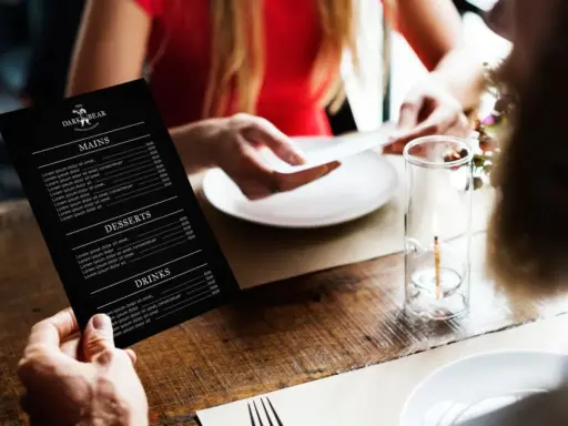 Mężczyzna trzyma czarne menu restauracji "The Dark Bear". Co to jest laminat? To trwałe menu, idealne do restauracji.