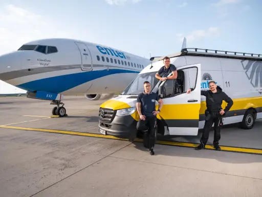 Trzech pracowników Enter Air stoi obok samolotu i vana. Chcesz wiedzieć, jak sprawdzić numer lotu Enter Air?