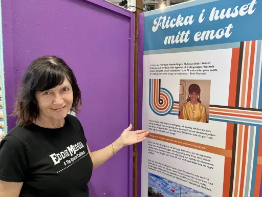 Kvinna i Eddie Meduza-tröja pekar på en utställning om "Flicka i huset mitt emot", en låt av Errol Norstedt.