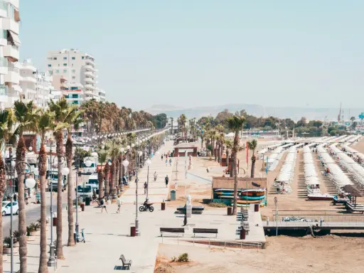 Promenada w Larnace z palmami, białymi budynkami i plażą pełną leżaków. Idealne miejsce, by zobaczyć, co oferuje Larnaka.