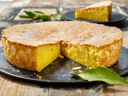 Una deliziosa caprese al limone, cosparsa di zucchero a velo e scorzetta d'arancia, con mandorle sui bordi.