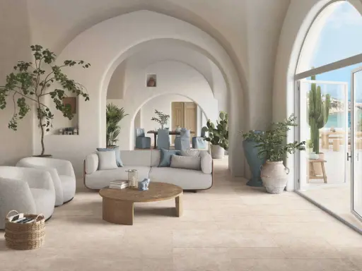 Un salon lumineux avec des arches, des plantes et un canapé confortable. Le sol en carrelage clair est idéal pour ce style méditerranéen. Quel revêtement de sol choisir ?