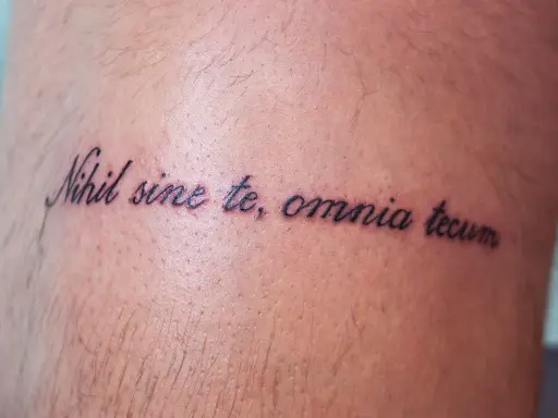 Tatuaż z łacińską sentencją "Nihil sine te, omnia tecum" na skórze.