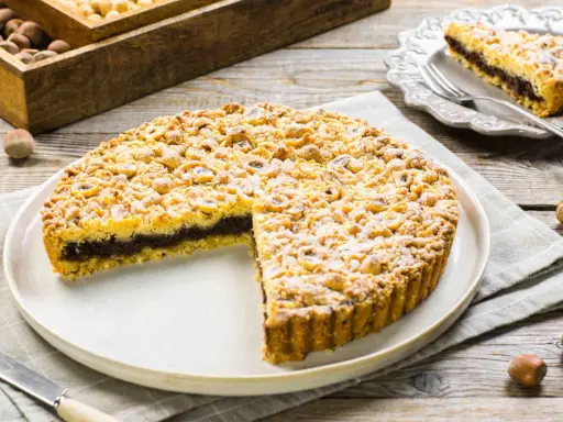 Sbriciolata alla Nutella con tante nocciole croccanti, un dolce invitante su un piatto bianco, pronto per essere gustato.