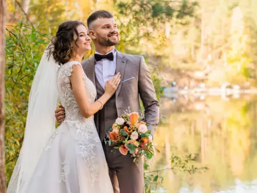 Młoda para w otoczeniu jesiennej przyrody. Ona w sukni ślubnej, on w garniturze. Trzymają bukiet. Zmieniła panieńskie nazwisko.
