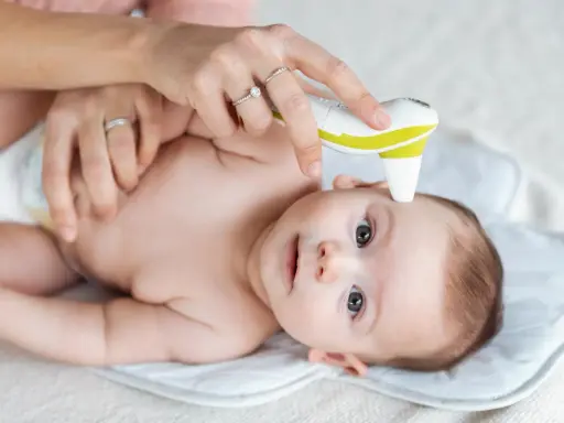 Mama mierzy temperaturę niemowlaka termometrem bezdotykowym.