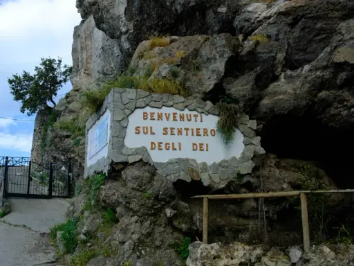 Qui inizia il Sentiero degli Dei, un cartello accoglie i visitatori tra rocce e vegetazione.