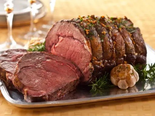 Saftiger Rinderbraten (1 kg) mit perfekter Kerntemperatur, garniert mit Rosmarin und Knoblauch auf einem Silbertablett.