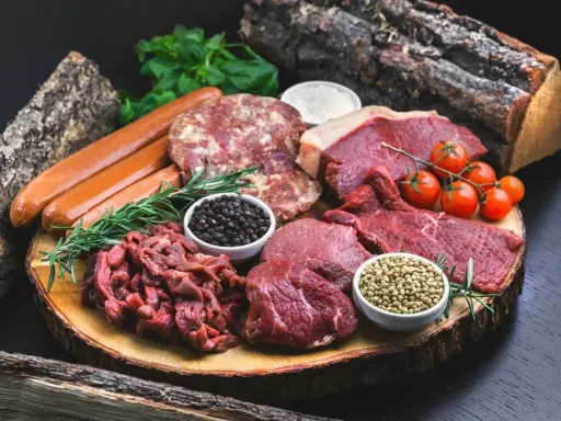 Mięso wołowe, kiełbaski, kotlety i przyprawy na desce. Idealne składniki dla diety carnivore.
