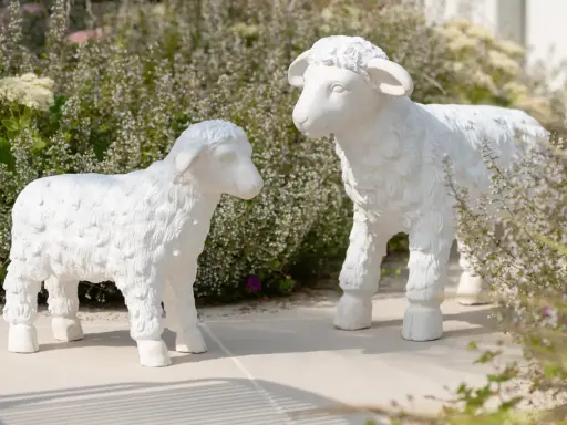 Deux adorables agneaux en résine, œuvres de sculpteurs animaliers, semblent converser au milieu d'une végétation luxuriante.