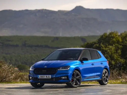 Un Skoda Fabia 130 azul brillante, con techo negro, aparcado en un paisaje montañoso.