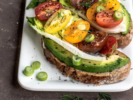 Herzhafte Avocado-Tomaten-Toasts auf Vollkornbrot, garniert mit Frühlingszwiebeln und Dill. Perfekt als kalorienarme Snacks für zwischendurch.