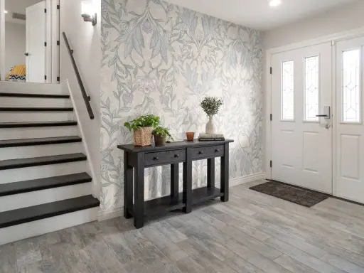 Hall med trappa och en konsol med växter. Vacker morris tapet inspiration med blommor och bladverk.