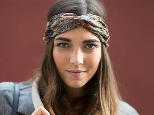 Frau mit braunen Haaren und einem gemusterten Haarband, das ihre Frisur mit Haarband unterstreicht.