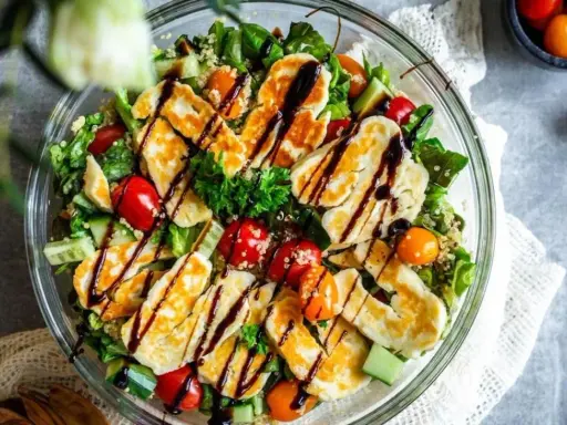 En härlig halloumi sallad med quinoa, körsbärstomater och gurka, ringlad med balsamvinäger. Perfekt för en lätt lunch.