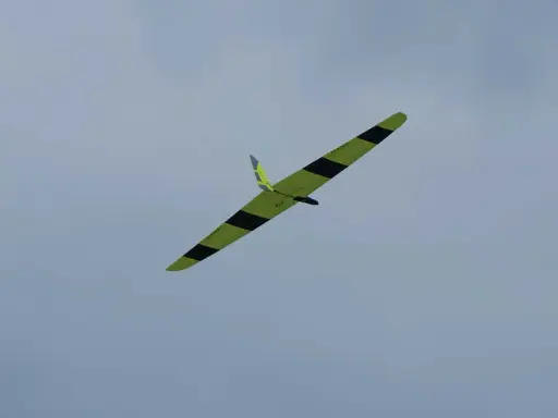 Ein gelb-schwarzes Flying Wing Segelflugzeug gleitet elegant durch den wolkenverhangenen Himmel.